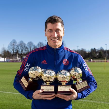 Robert Lewandowski holding his personal trophies while playing with Bayern Munich